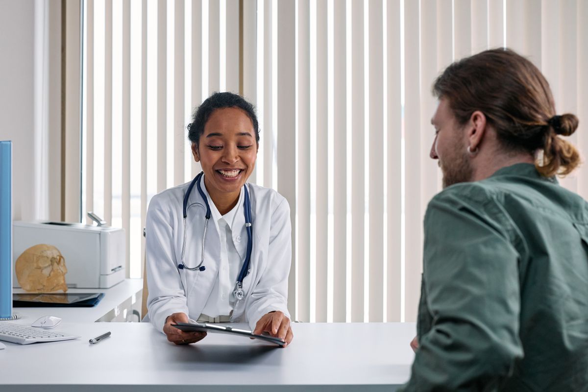 Médica sorrindo enquanto conversa com um paciente durante a consulta